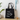 Black tote bag with 'Coffee. Walk. Repeat.' text and paw prints on a wooden surface.