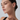 Close-up of a woman wearing a delicate gold ear cuff earring, shown in profile against a light gray studio background.