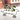 Three small glass vases with green plants on a black wire stand against a blurred background.