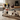 Two ceramic dog figurines with black, white, and brown colors on a textured beige background.