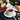 Tea cup with a white dog-shaped tea infuser, surrounded by flowers and pastries on a dark surface.