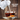 White teapot with a no-drip spout pouring tea into a glass cup on a wooden surface.